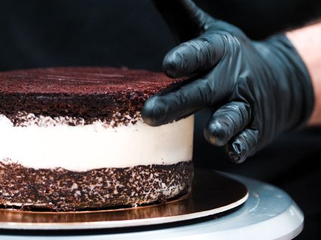 Chef cake designer preparing layered creamy cake base for frosted decoration and topping