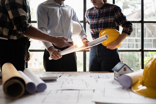 Architect team working with blueprints for architectural plan, engineer sketching a construction project, green energy concept.