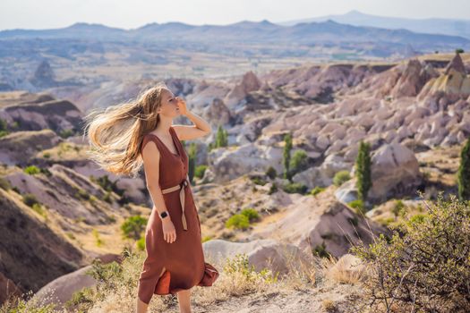 Young woman exploring valley with rock formations and fairy caves near Goreme in Cappadocia Turkey.