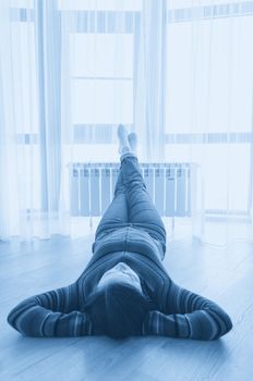 Woman laying on floor with feet raised up on radiator for warming