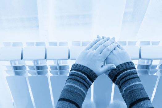 Girl warms up the frozen hands above hot radiator, close up