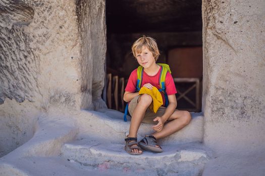 Boy tourist exploring valley with rock formations and fairy caves near Goreme in Cappadocia Turkey.