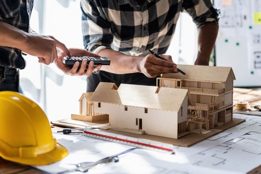 Architect team working with blueprints for architectural plan, engineer sketching a construction project, green energy concept.