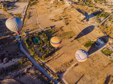 Colorful hot air balloons flying over at fairy chimneys valley in Nevsehir, Goreme, Cappadocia Turkey. Spectacular panoramic drone view of the underground city and ballooning tourism. High quality.