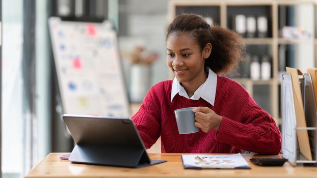 Portrait of beautiful young black woman using laptop at cafe.