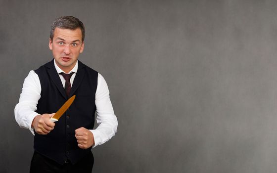 Studio portrait of an angry man with a knife. A cute aggressive man of 30-35 years old with a knife looks at the camera. High quality photo