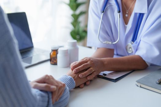 Doctor having conversation with patient while discussing explaining symptom and hold hand for encourage.