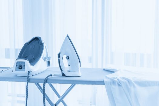 Steam generator iron standing on ironing board near panoramic window