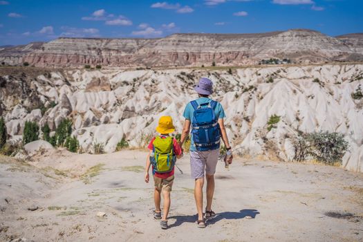Father and son tourists exploring valley with rock formations and fairy caves near Goreme in Cappadocia Turkey.