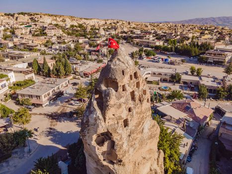 Turkish flag on the hill with typical tuff rock formations of the Cappadocia against the backdrop of a blue sky, Goreme, Turkey.