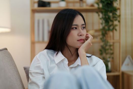 Young asian woman feeling miserable and lonely on sofa at home.