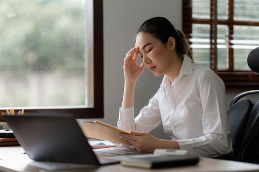 Stressed Asian business woman worry with many document on desk at office. Businesswoman working at home.