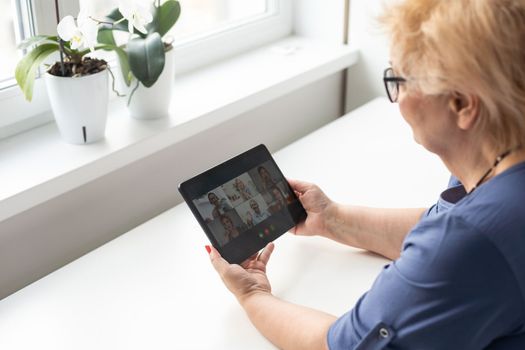 telemedicine concept, old woman with tablet pc during an online consultation with her doctor in her living room.