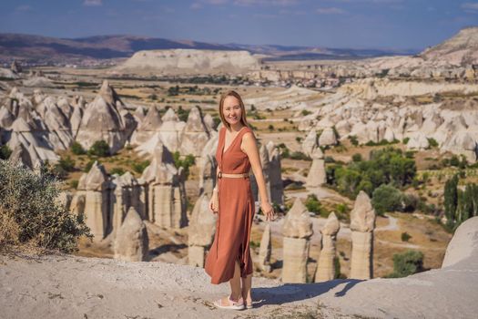 Young woman exploring valley with rock formations and fairy caves near Goreme in Cappadocia Turkey.