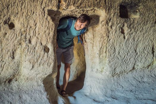 Young man exploring valley with rock formations and fairy caves near Goreme in Cappadocia Turkey.