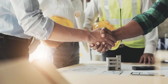 Professional Asian male engineer shaking hands with male architect after the meeting..