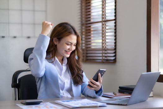Portrait of an excited young asian girl using laptop computer and celebrating success for online...