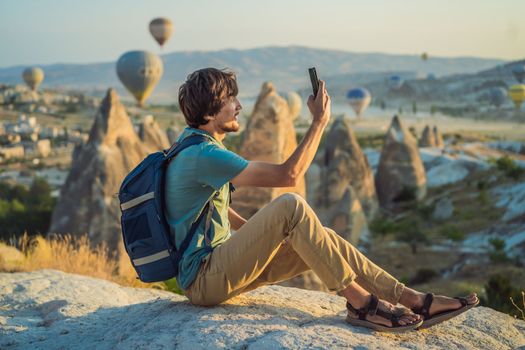 Tourist man looking at hot air balloons in Cappadocia, Turkey. Happy Travel in Turkey concept. Man on a mountain top enjoying wonderful view.