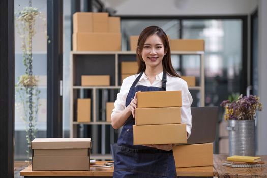 Portrait of young Asian woman working SME with a box at home the workplace.start-up small business owner, small business entrepreneur SME or freelance business online and delivery concept...