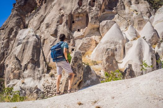 Young man exploring valley with rock formations and fairy caves near Goreme in Cappadocia Turkey.