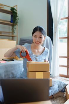 Starting small business entrepreneur of independent Asian female online seller packing products to send to customers and SME delivery concept.