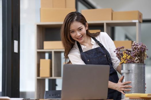 A portrait of a small startup, an SME owner, an Asian female entrepreneur checking orders to arrange the produce before packing the products in the inner boxes with the customers. Freelance concepts..