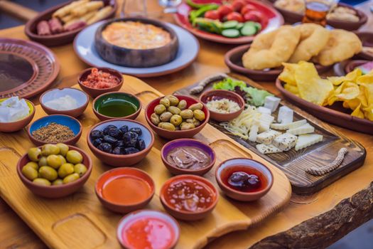 Turkish breakfast table. Pastries. Vegetables. Olives. Cheeses, fried eggs. Jams, tea in copper pot and tulip glasses. Wide composition.