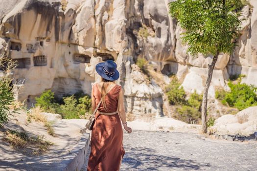 Young woman exploring valley with rock formations and fairy caves near Goreme in Cappadocia Turkey.