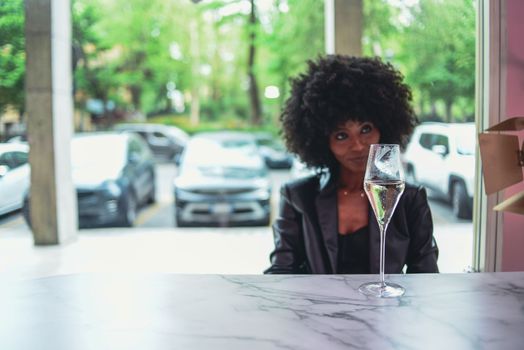 Young attractive African woman with happy cheerful smile drinking and having fun in a bar