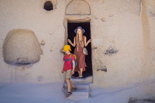 Mom and son tourists exploring valley with rock formations and fairy caves near Goreme in Cappadocia Turkey.