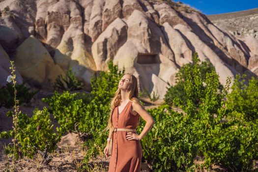 Young woman exploring valley with rock formations and fairy caves near Goreme in Cappadocia Turkey.