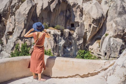 Young woman exploring valley with rock formations and fairy caves near Goreme in Cappadocia Turkey.