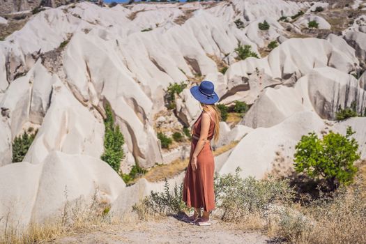 Young woman exploring valley with rock formations and fairy caves near Goreme in Cappadocia Turkey.