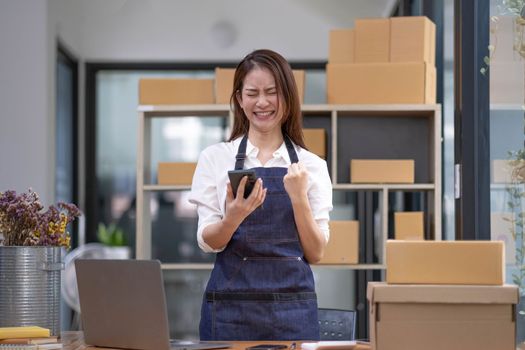 Entrepreneur of beautiful business asian young woman working online with laptop and celebrating at home with her work success cheerful and happiness. Small Business Startup concept..