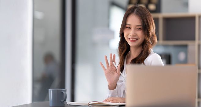 Asian woman working in office and discussing with business partner via laptop video call, young Asian business woman is business executive, founding startup executive. Startup business concept...