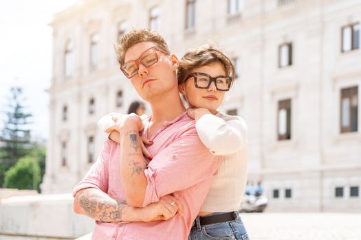 Young beautiful hipster couple in love walking on old city street, summer Europe vacation, travel, fun, happy, smiling, glasses, trendy outfit, romance, date, embracing