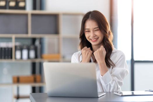 Beautiful asian woman using laptop computer, exciting and celebrating with good news of business successful. Small business startup concept...