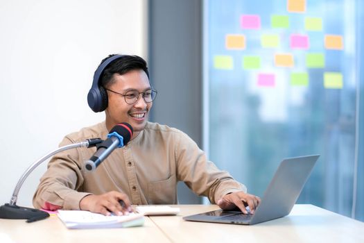 Young man recording podcast using microphone and laptop happy face smiling Positive person
