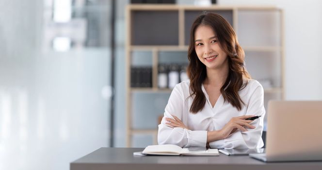 Charming Asian woman working at the office using a laptop Looking at the camera...