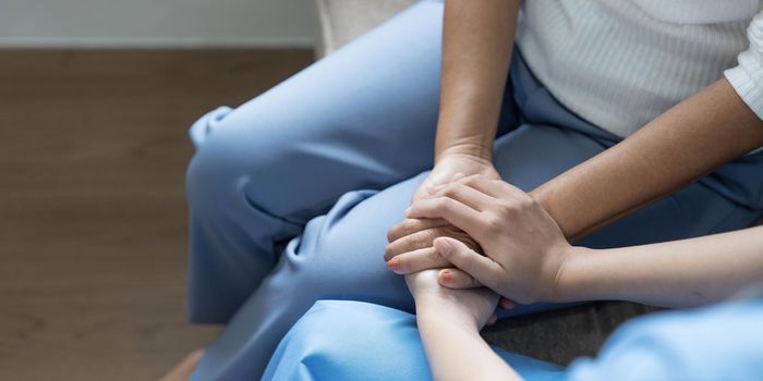 Happy patient is holding caregiver for a hand while spending time together. Elderly woman in nursing home and nurse...