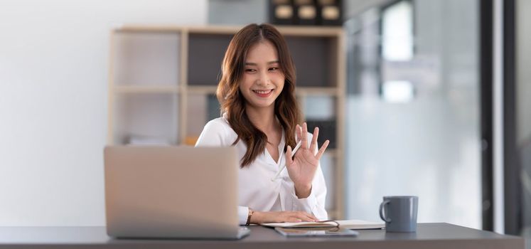 Asian woman working in office and discussing with business partner via laptop video call, young Asian business woman is business executive, founding startup executive. Startup business concept...