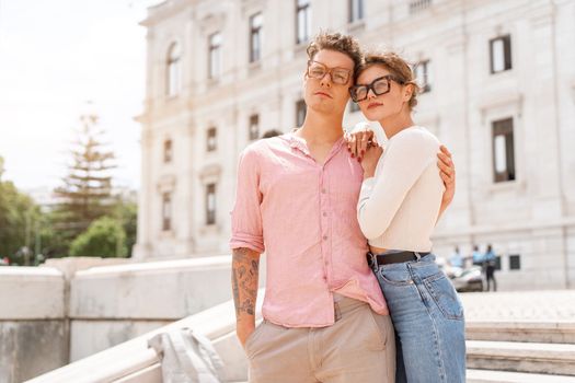 Young beautiful hipster couple in love walking on old city street, summer Europe vacation, travel, fun, happy, smiling, glasses, trendy outfit, romance, date, embracing