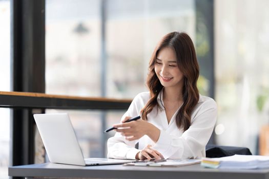 Young beautiful asian businesswoman working on tablet with happiness while sitting at the table in modern office room...