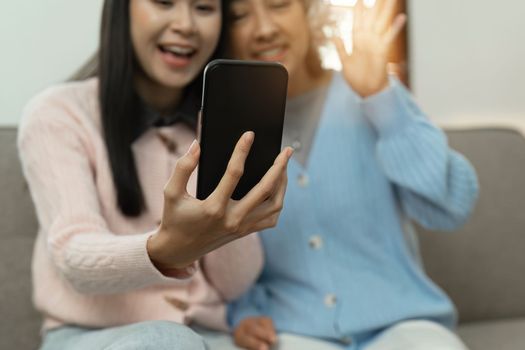 Senior woman and adult daughter look at cell phone screen communicating with family. older woman using cell phone to video call.