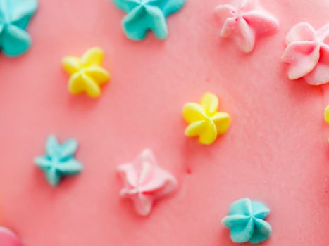 Close up of pink frosted dripping cake with donut and plastel brushed royal star sprinkles insolated on white studio shot