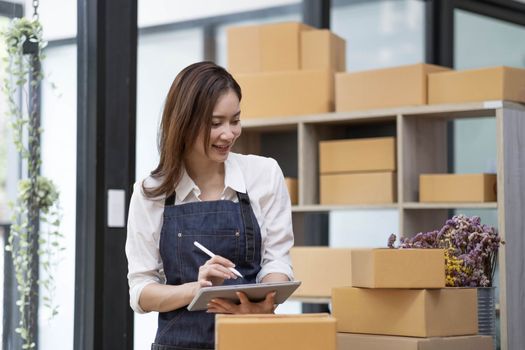 A portrait of a small startup, an SME owner, an Asian female entrepreneur checking orders to arrange the produce before packing the products in the inner boxes with the customers. Freelance concepts..