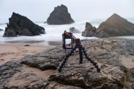 Digital mirrorless photo camera on flexible tripod to making photo of sea landscape. Photocamera on articulated tripod