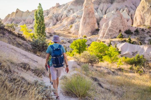 Young man exploring valley with rock formations and fairy caves near Goreme in Cappadocia Turkey.