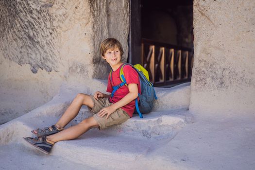 Boy tourist exploring valley with rock formations and fairy caves near Goreme in Cappadocia Turkey.