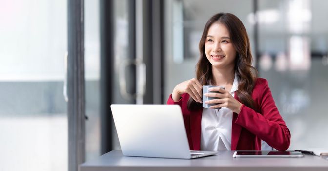 Portrait of smiling beautiful business asian woman in pink suit working in home office desk using computer. Business people employee freelance online marketing e-commerce, work from home concept..